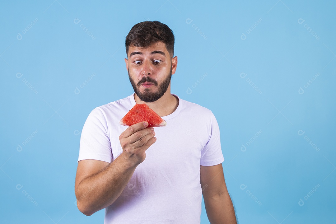 Homem jovem se alimentando com melancia sobre fundo isolado