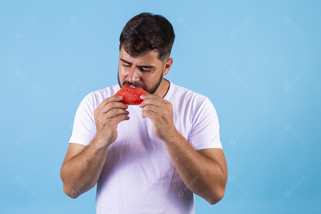 Homem jovem se alimentando com melancia sobre fundo isolado