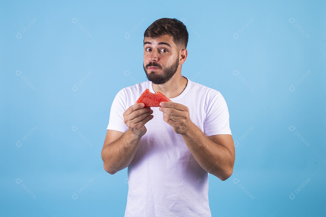 Homem jovem se alimentando com melancia sobre fundo isolado