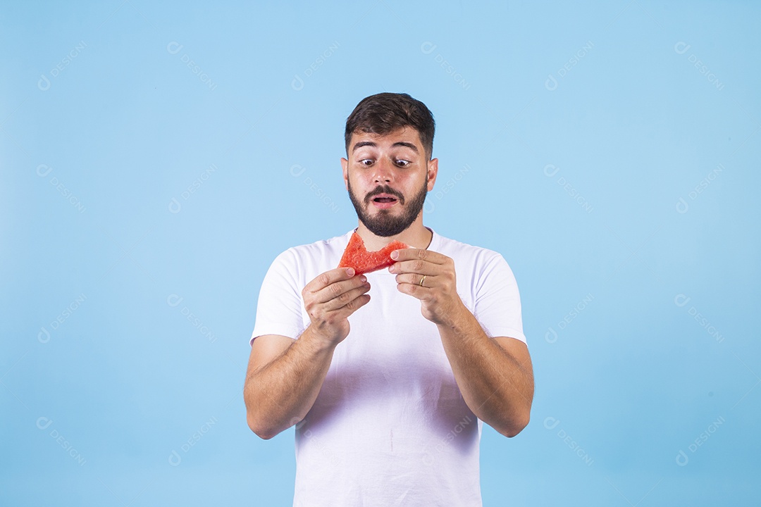 Homem jovem se alimentando com melancia sobre fundo isolado
