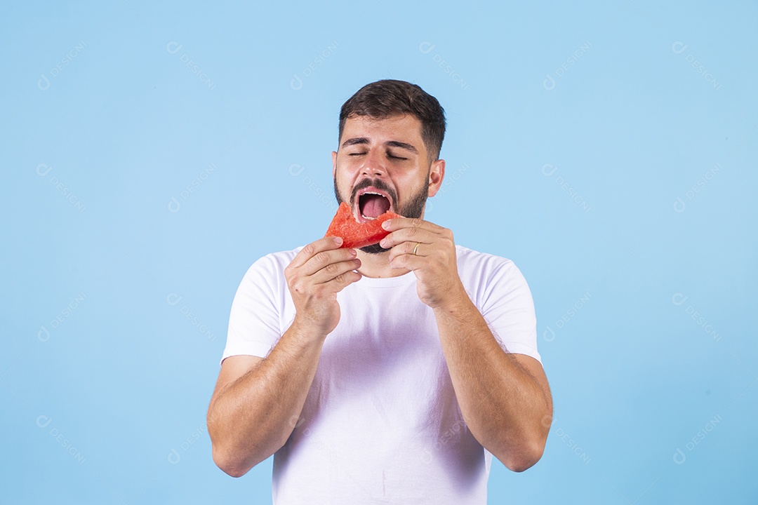 Homem jovem se alimentando com melancia sobre fundo isolado