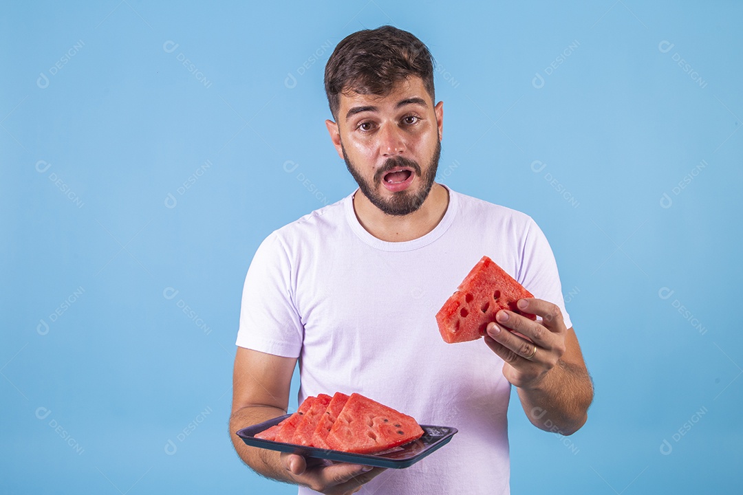 Homem jovem se alimentando com melancia sobre fundo isolado