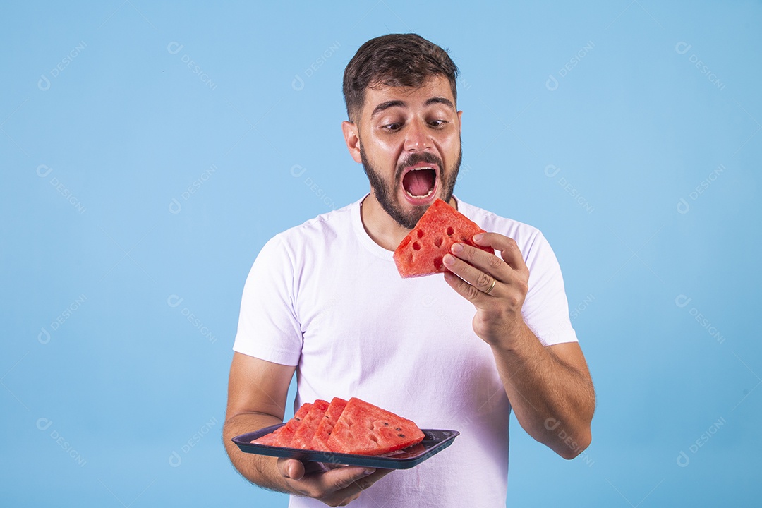 Homem jovem se alimentando com melancia sobre fundo isolado