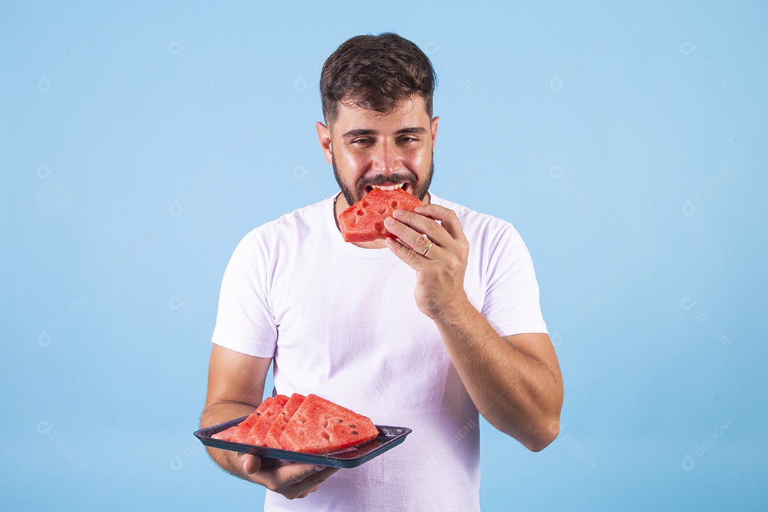 Homem jovem se alimentando com melancia sobre fundo isolado