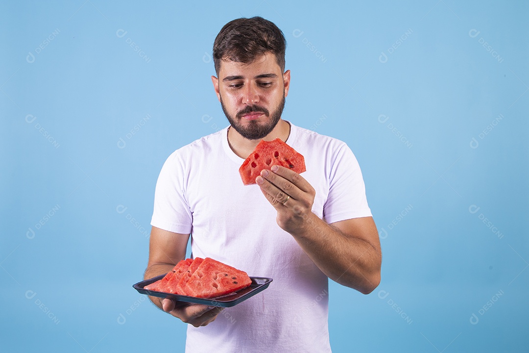 Homem jovem se alimentando com melancia sobre fundo isolado