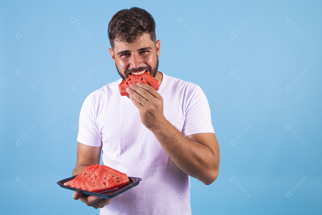 Homem jovem se alimentando com melancia sobre fundo isolado