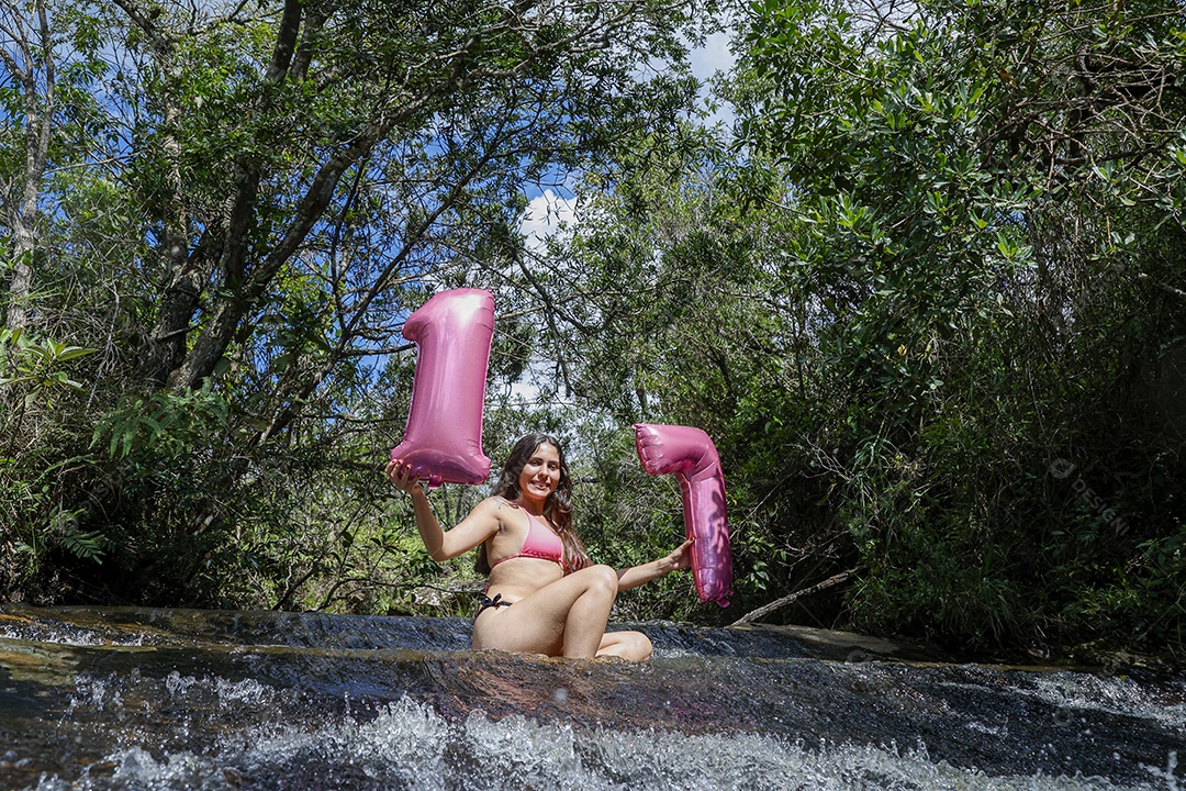 Linda mulher jovem fazendo aniversario completando 17 anos sobre cachoeira