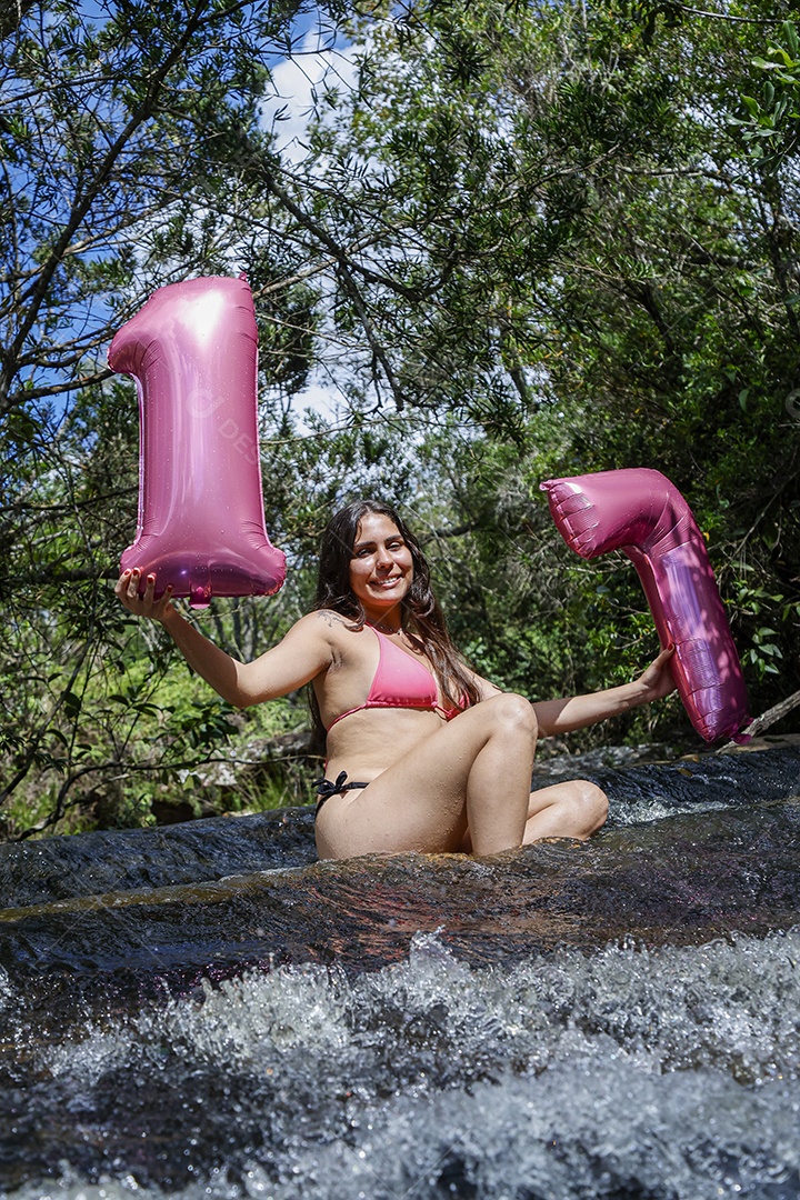 Linda mulher jovem fazendo aniversario completando 17 anos sobre cachoeira