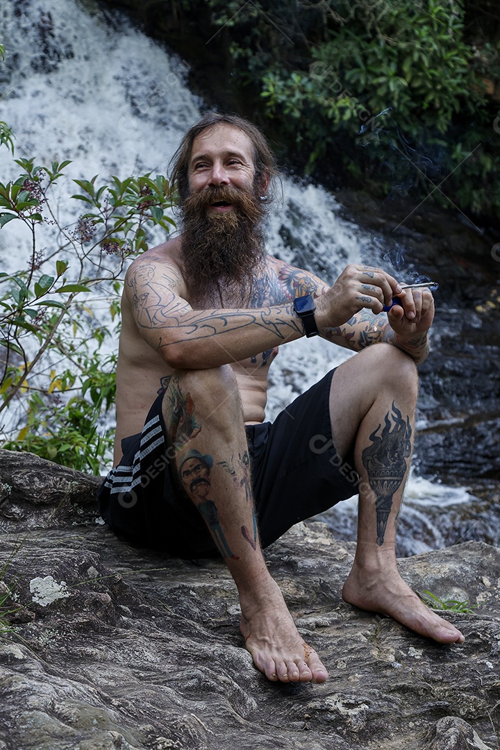 Homem barbudo fumando cannabis sobre cachoeira