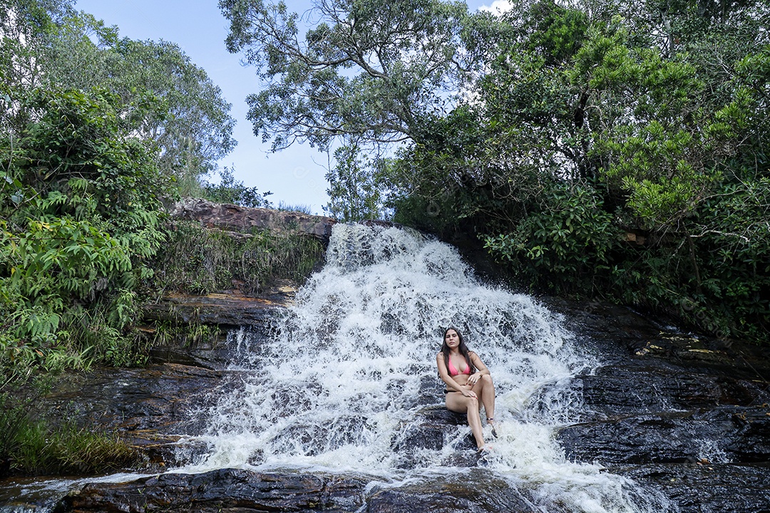 Linda mulher jovem usando biquíni sobre cachoeira