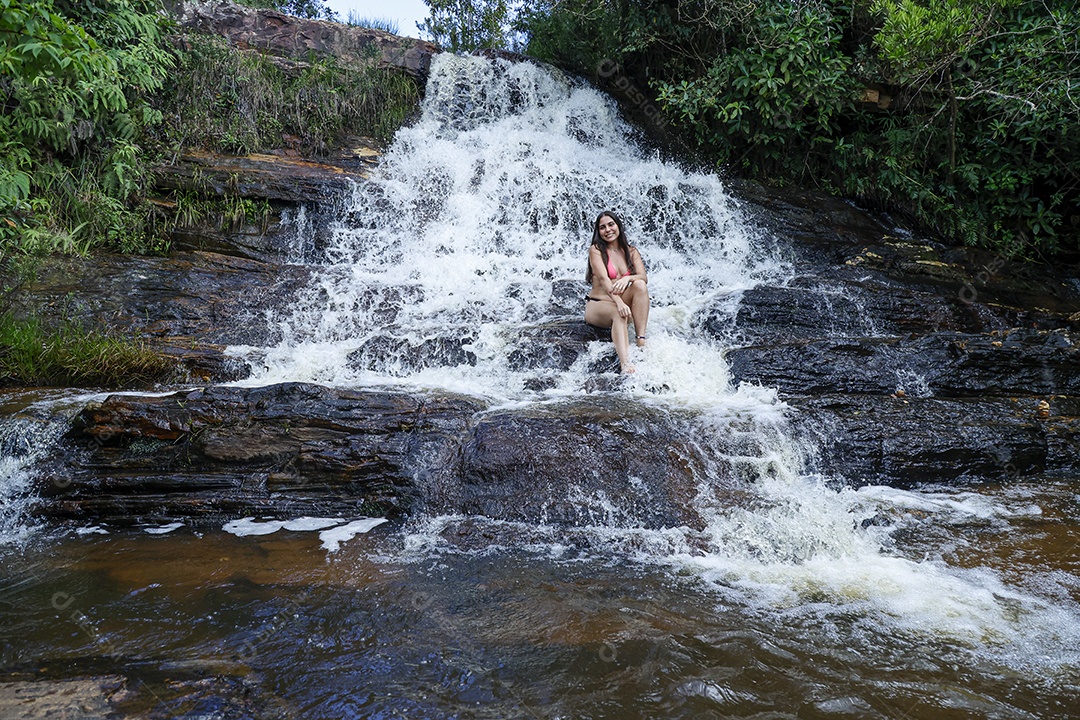 Linda mulher jovem usando biquíni sobre cachoeira
