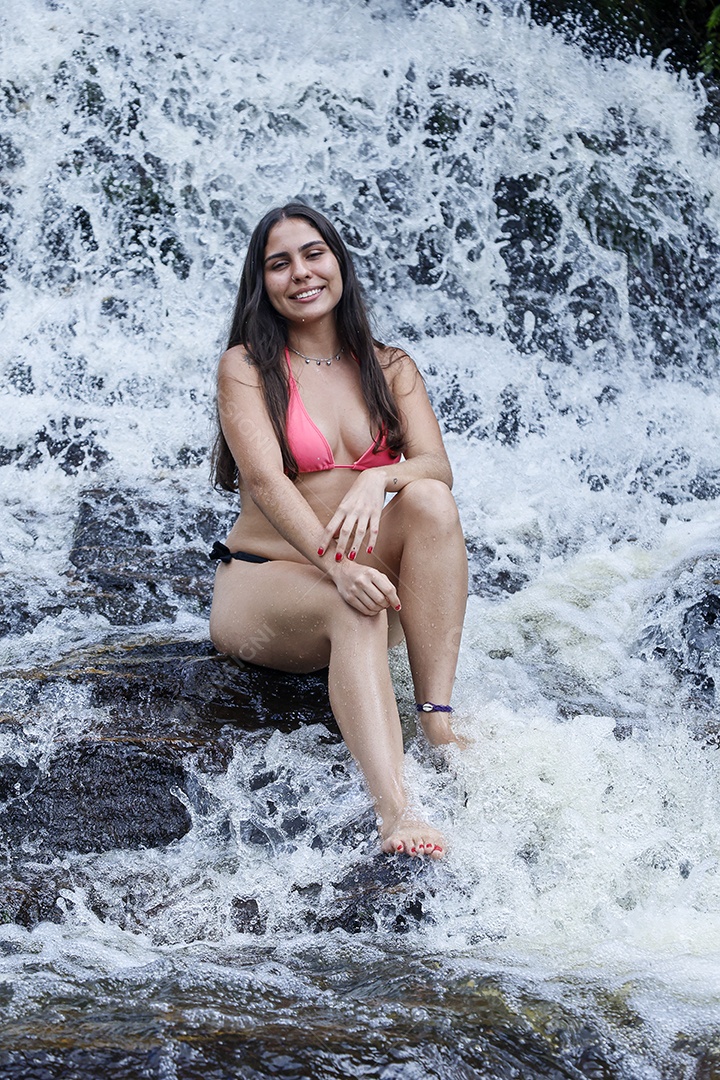 Linda mulher jovem usando biquíni sobre cachoeira