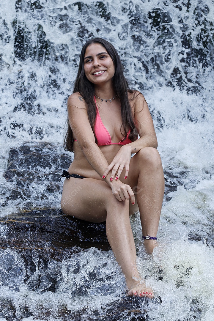 Linda mulher jovem usando biquíni sobre cachoeira