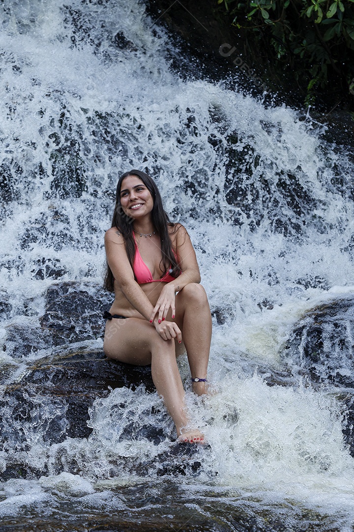 Linda mulher jovem usando biquíni sobre cachoeira