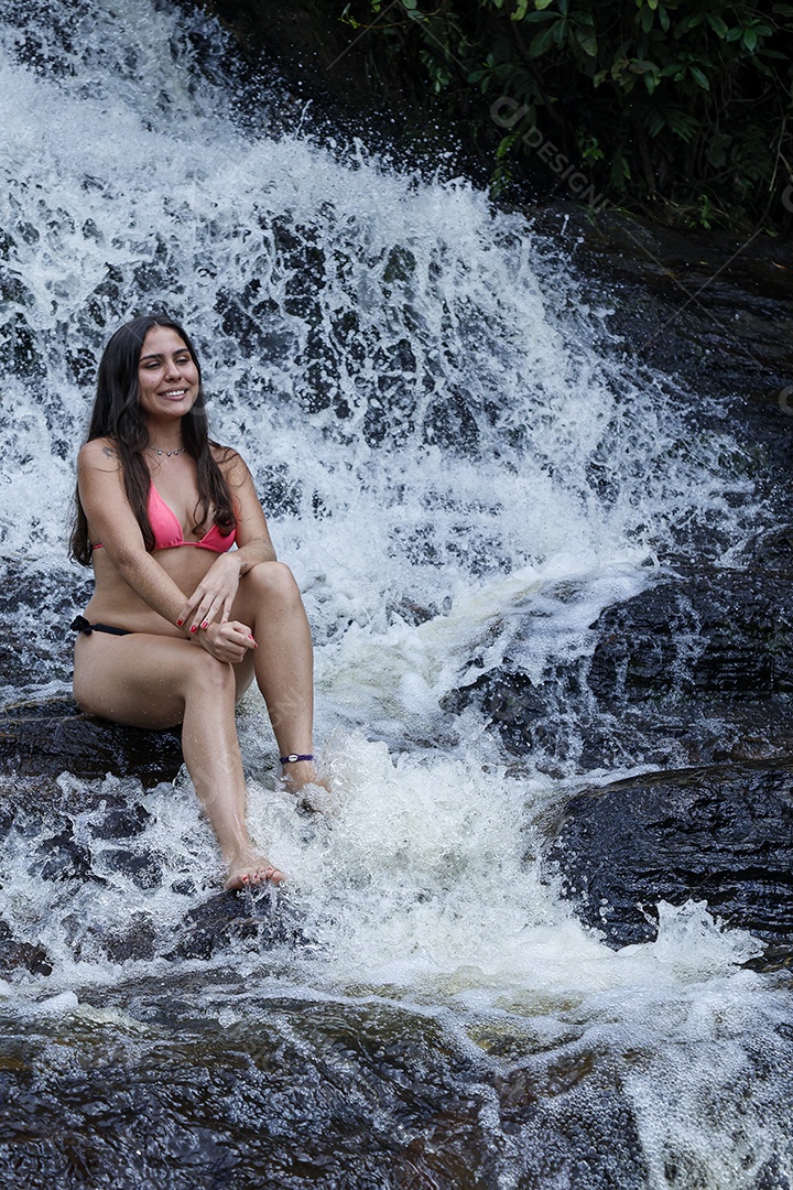 Linda mulher jovem usando biquíni sobre cachoeira