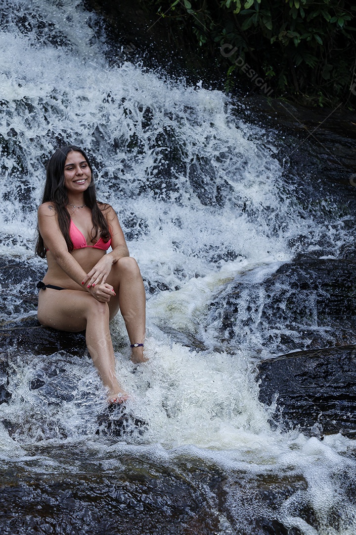 Linda mulher jovem usando biquíni sobre cachoeira