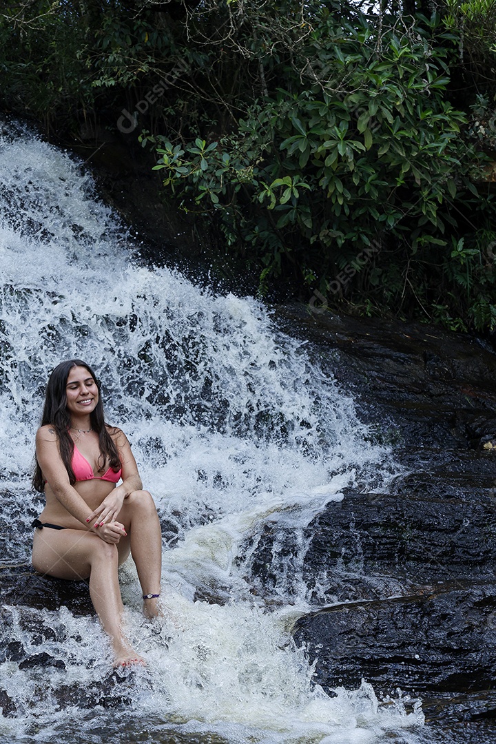 Linda mulher jovem usando biquíni sobre cachoeira