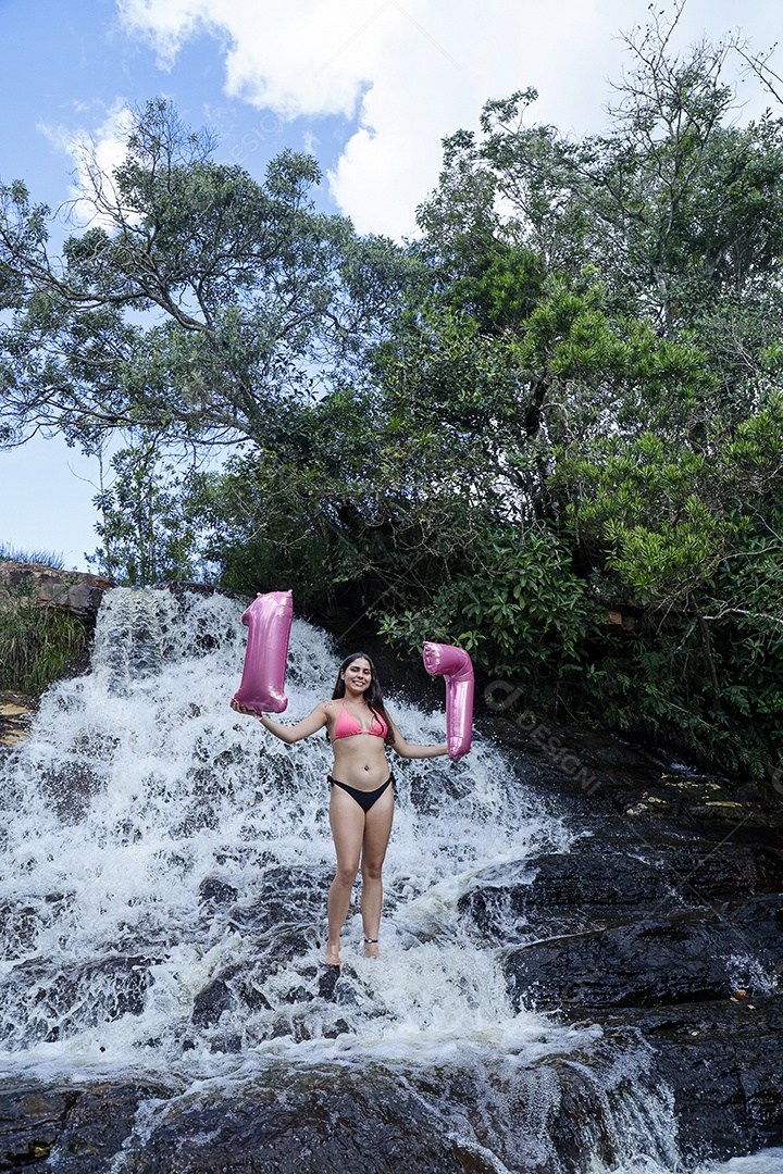 Linda mulher jovem fazendo aniversario completando 17 anos sobre cachoeira