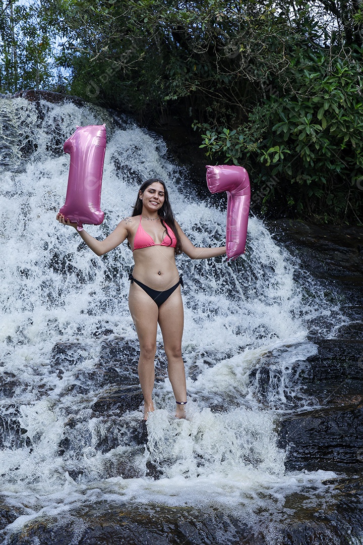 Linda mulher jovem fazendo aniversario completando 17 anos sobre cachoeira