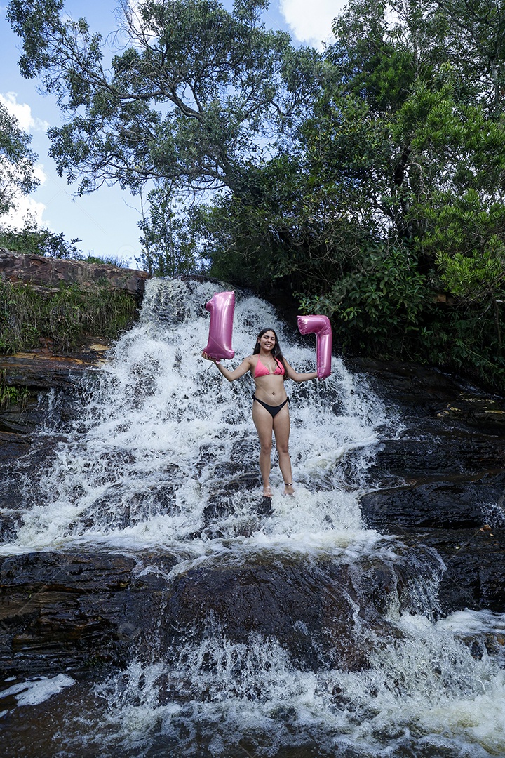 Linda mulher jovem fazendo aniversario completando 17 anos sobre cachoeira
