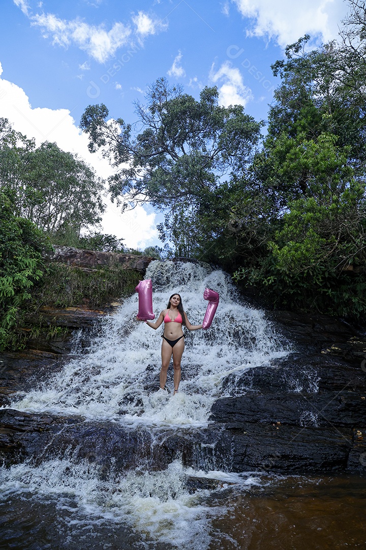 Linda mulher jovem fazendo aniversario completando 17 anos sobre cachoeira