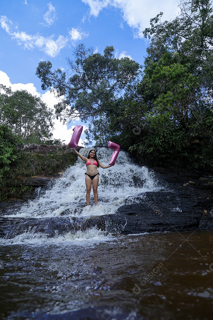 Linda mulher jovem fazendo aniversario completando 17 anos sobre cachoeira