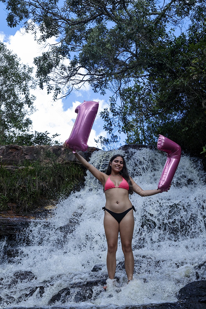 Linda mulher jovem fazendo aniversario completando 17 anos sobre cachoeira