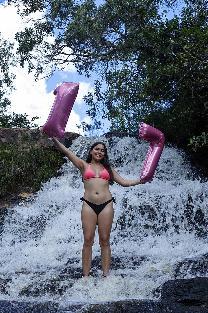 Linda mulher jovem fazendo aniversario completando 17 anos sobre cachoeira