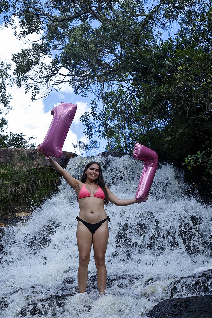 Linda mulher jovem fazendo aniversario completando 17 anos sobre cachoeira