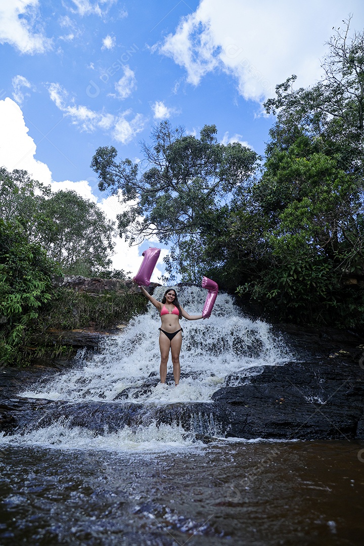 Linda mulher jovem fazendo aniversario completando 17 anos sobre cachoeira