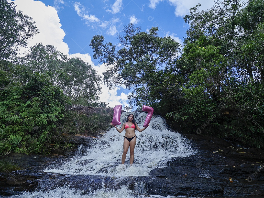 Linda mulher jovem fazendo aniversario completando 17 anos sobre cachoeira