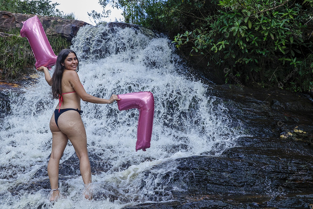Linda mulher jovem fazendo aniversario completando 17 anos sobre cachoeira