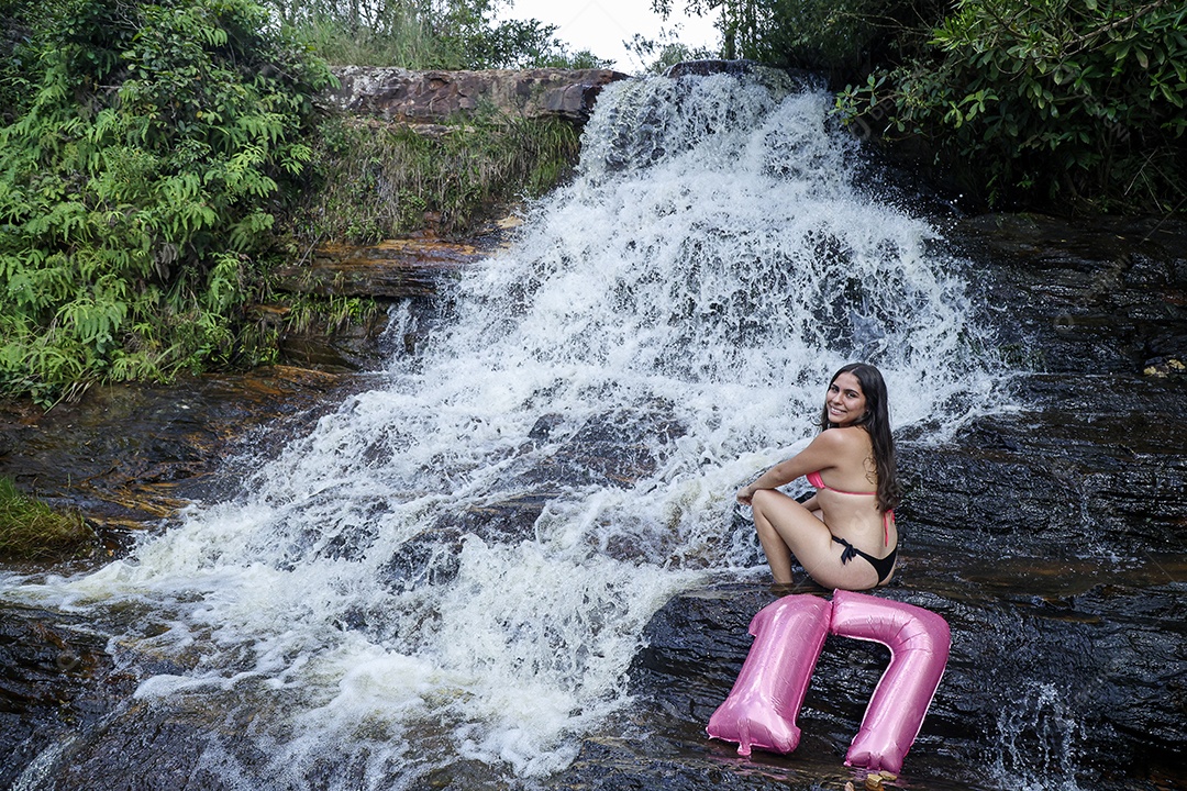 Linda mulher jovem fazendo aniversario completando 17 anos sobre cachoeira