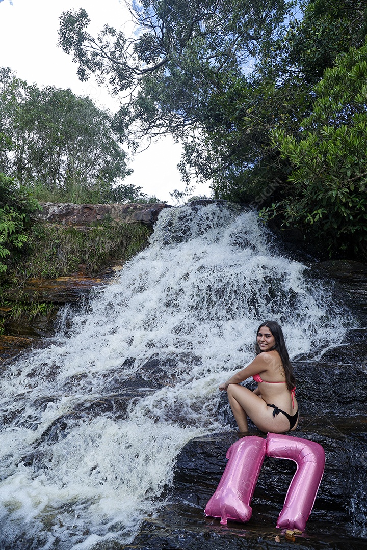 Linda mulher jovem fazendo aniversario completando 17 anos sobre cachoeira