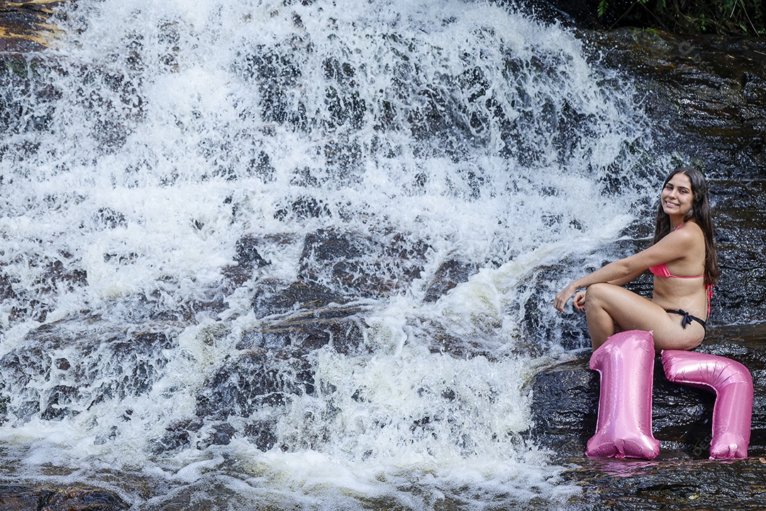 Linda mulher jovem fazendo aniversario completando 17 anos sobre cachoeira