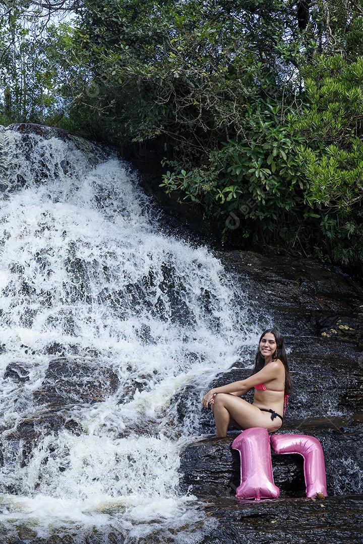 Linda mulher jovem fazendo aniversario completando 17 anos sobre cachoeira