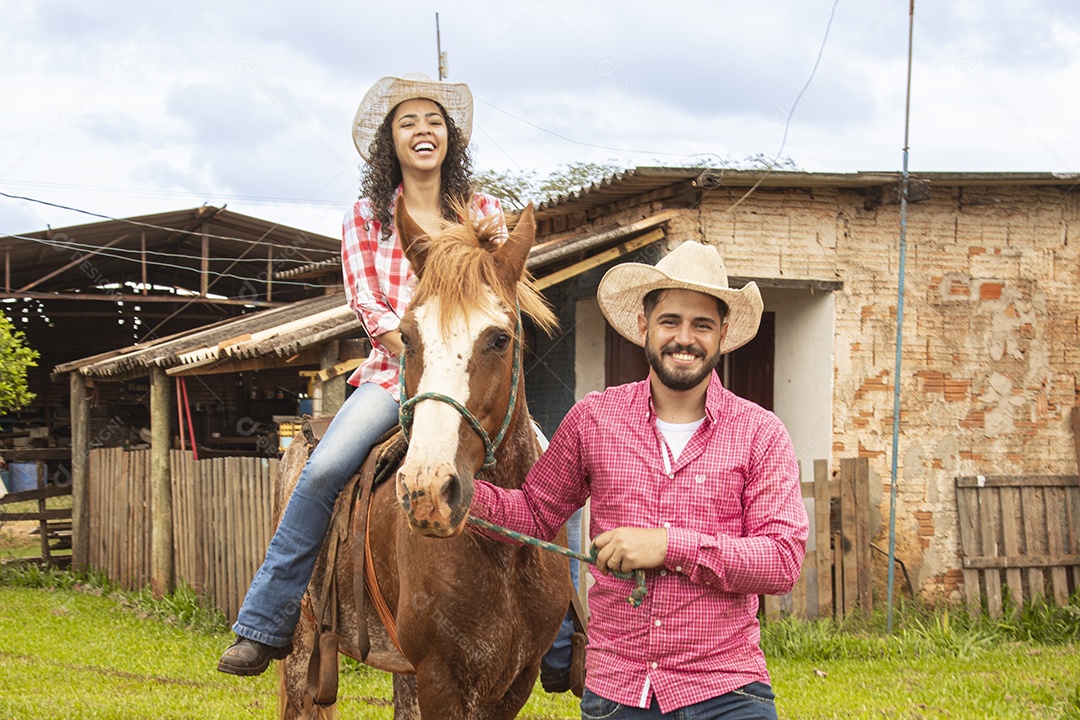 Casal de jovens sobre fazenda andando a cavalo sobre fazenda