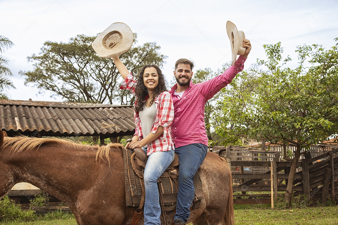 Casal de jovens sobre fazenda andando a cavalo sobre fazenda
