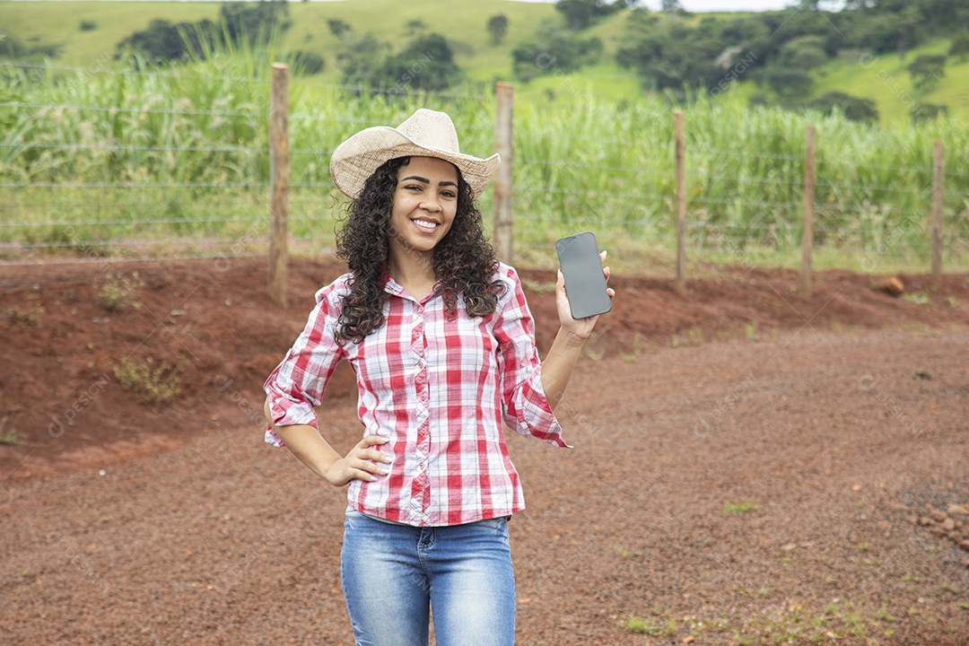 Agricultora mexendo em seu celular smartphone sobre fazenda
