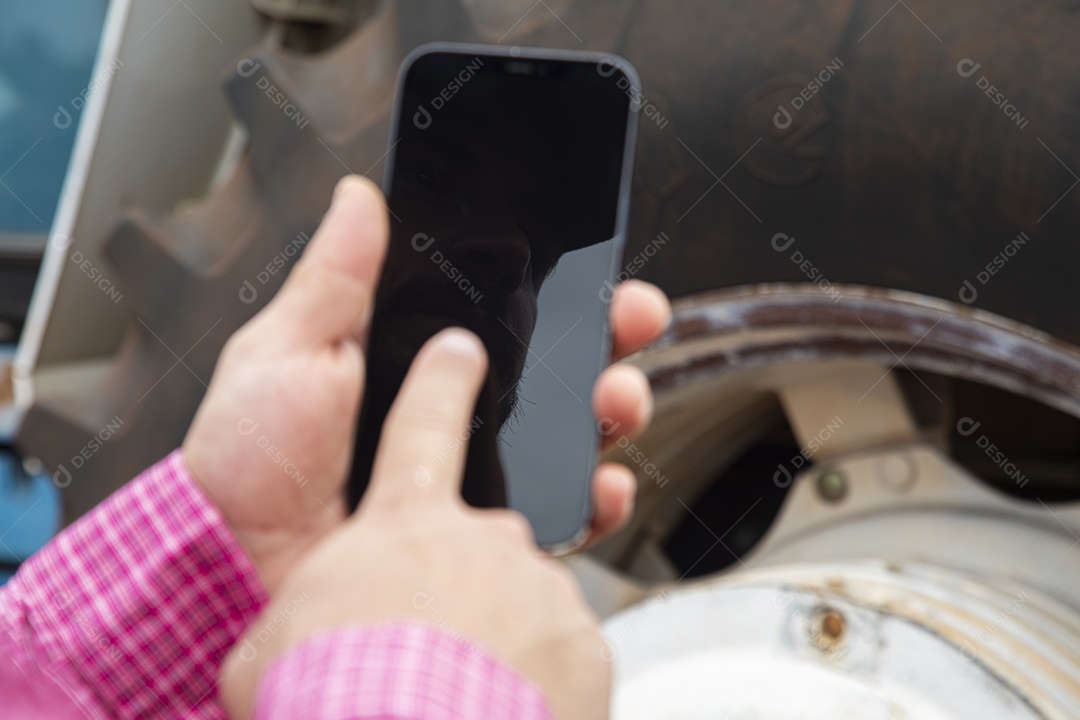 Agricultor mexendo em seu celular smartphone sobre seu trator em uma fazenda