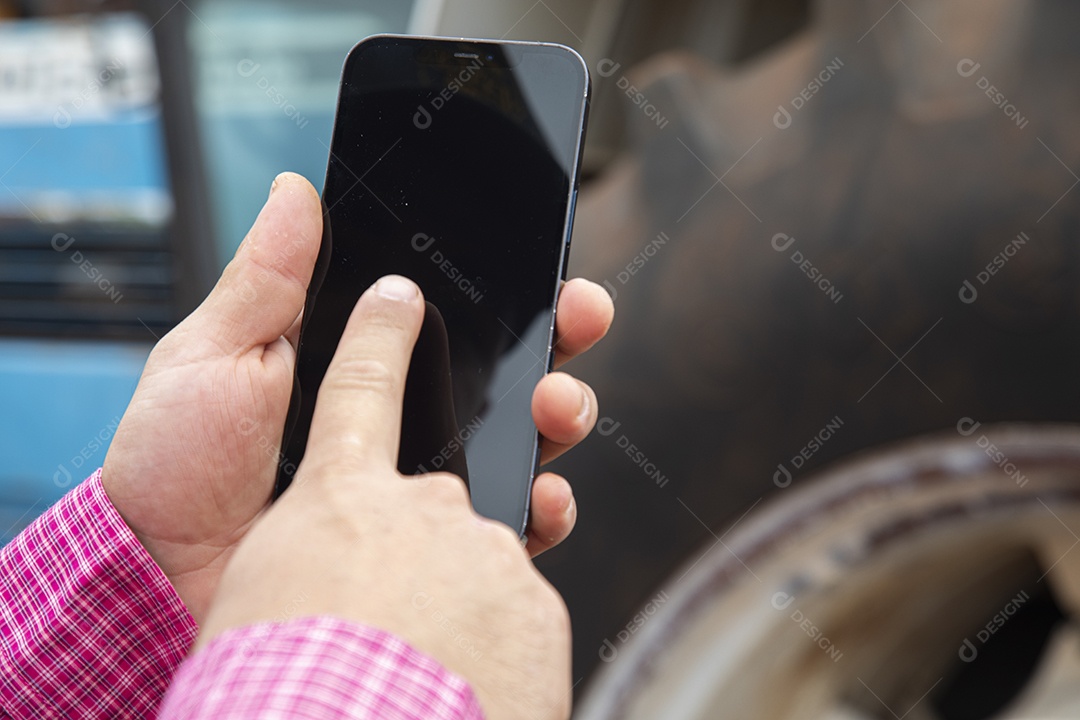 Agricultor mexendo em seu celular smartphone sobre seu trator em uma fazenda