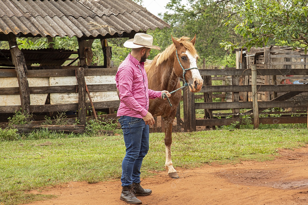 Homem jovem agricultor sobre fazenda com seu cavalo