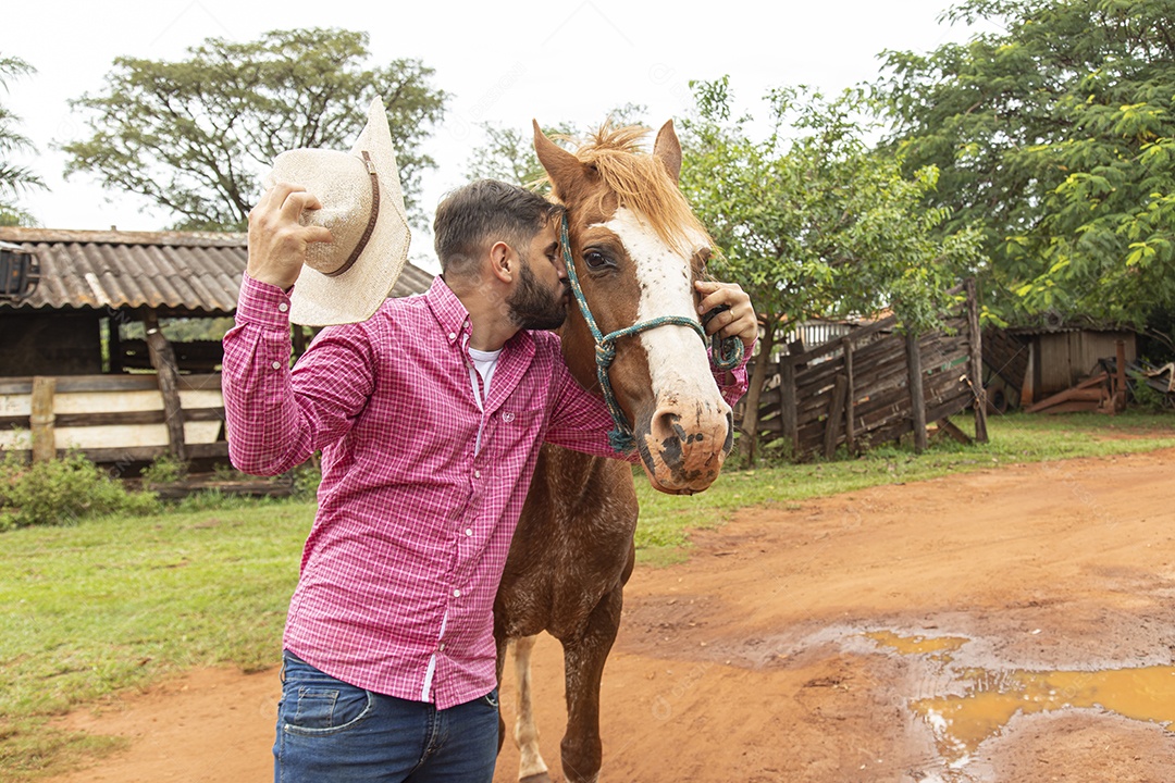 Homem jovem agricultor sobre fazenda com seu cavalo