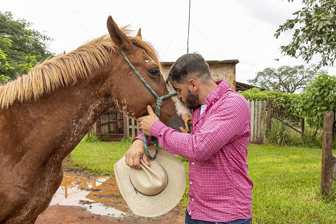 Homem jovem agricultor sobre fazenda com seu cavalo