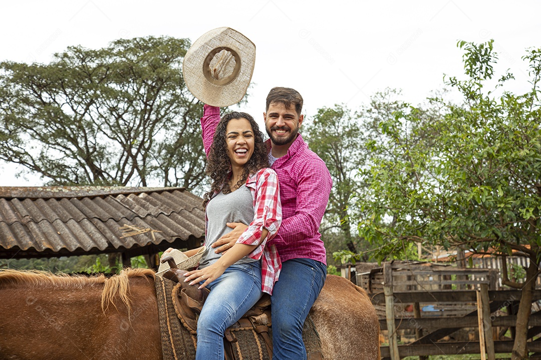 Casal de jovens sobre fazenda andando a cavalo sobre fazenda