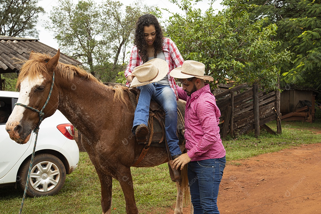 Homem ajudando sua namorada montar a cavalo sobre fazenda