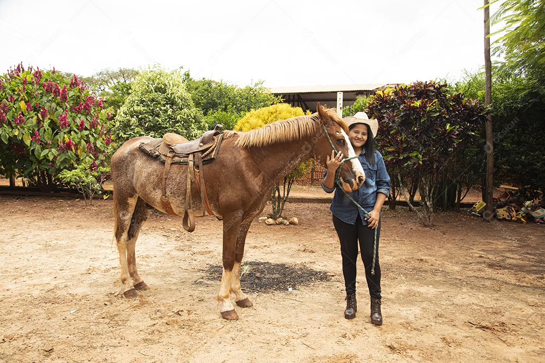 Mulher jovem agricultora sobre fazenda com seu cavalo