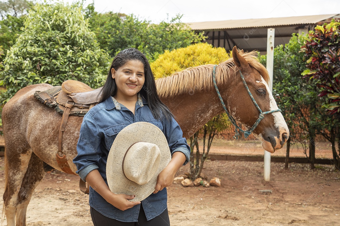 Mulher jovem agricultora sobre fazenda com seu cavalo