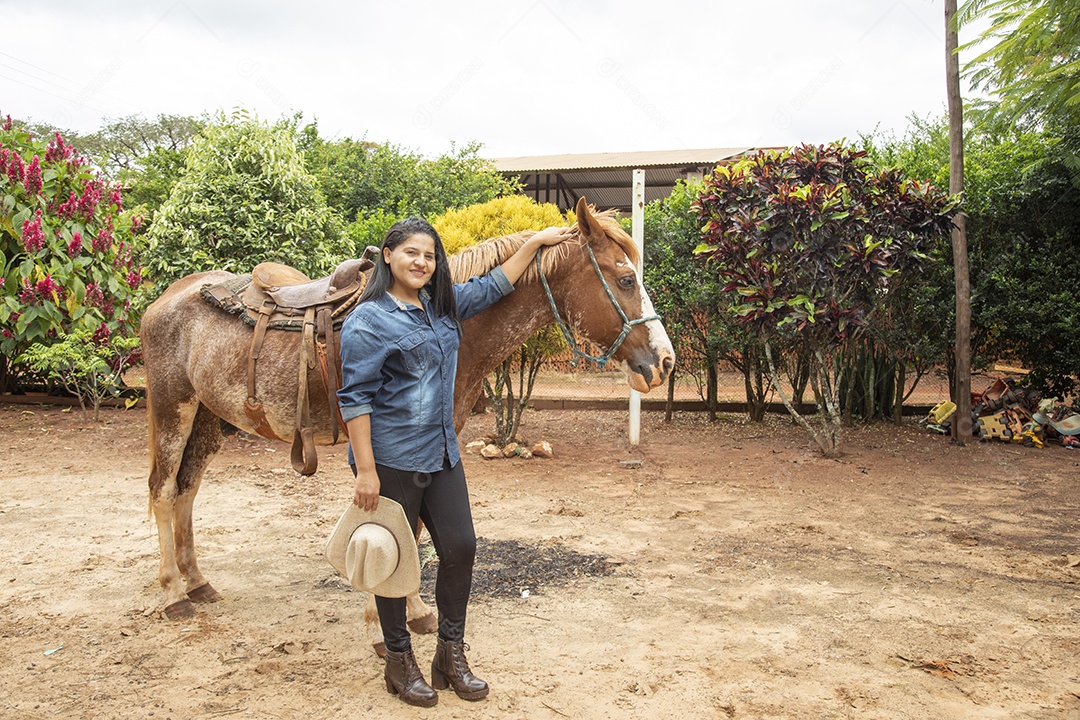 Mulher jovem agricultora sobre fazenda com seu cavalo