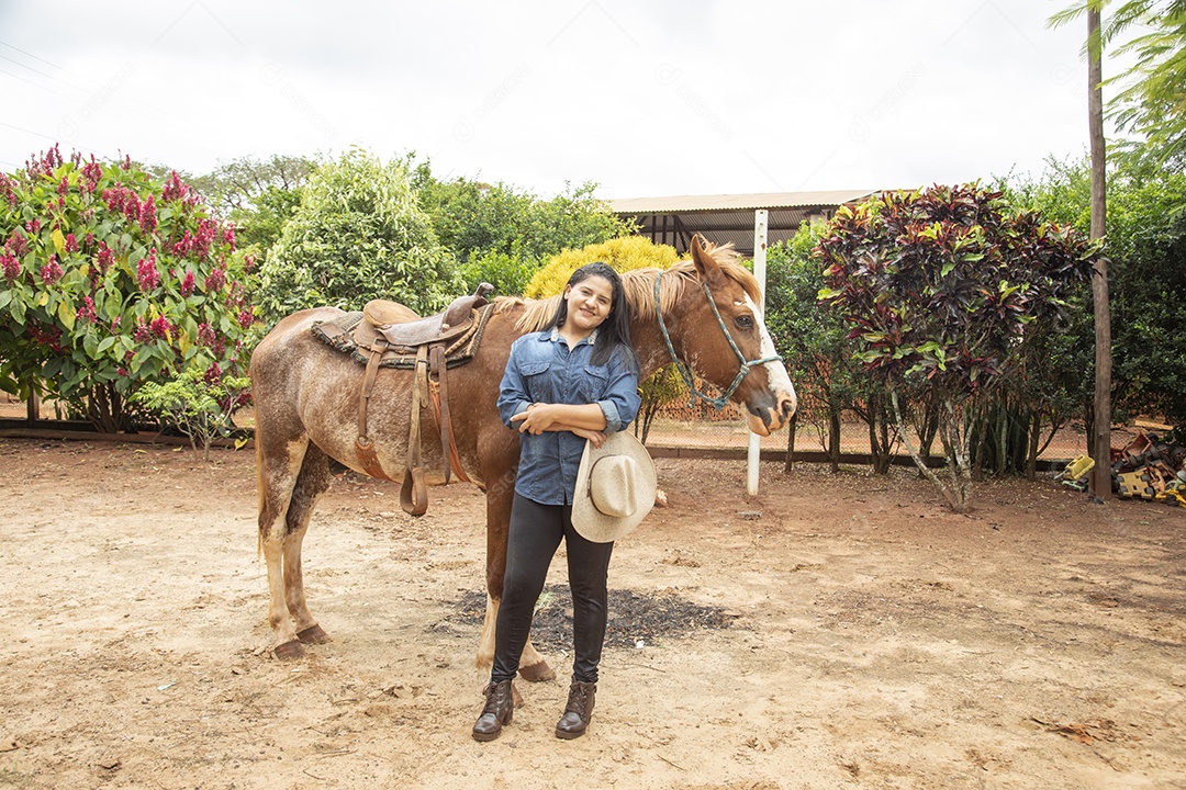 Mulher jovem agricultora sobre fazenda com seu cavalo